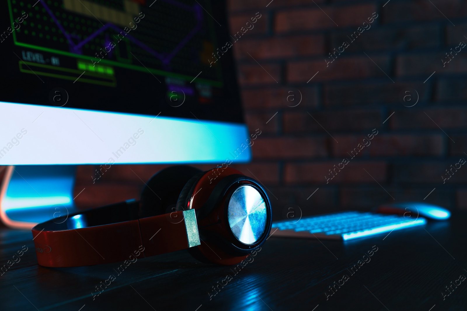 Photo of Modern computer and headphones on table in dark room. Playing video games