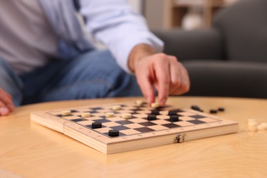 Man playing checkers at wooden table, closeup