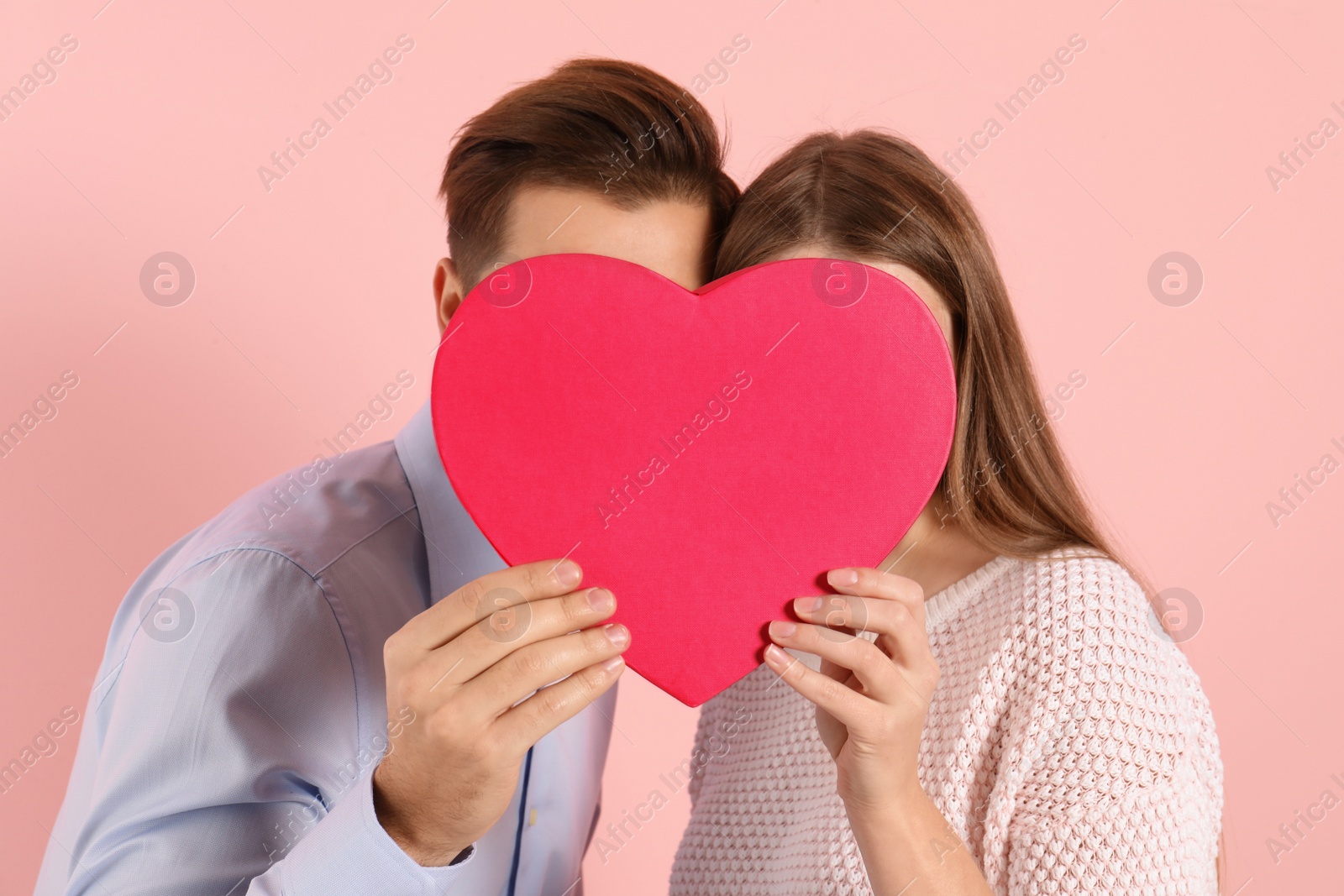Photo of Man and woman hiding behind decorative heart on color background. Valentine's day