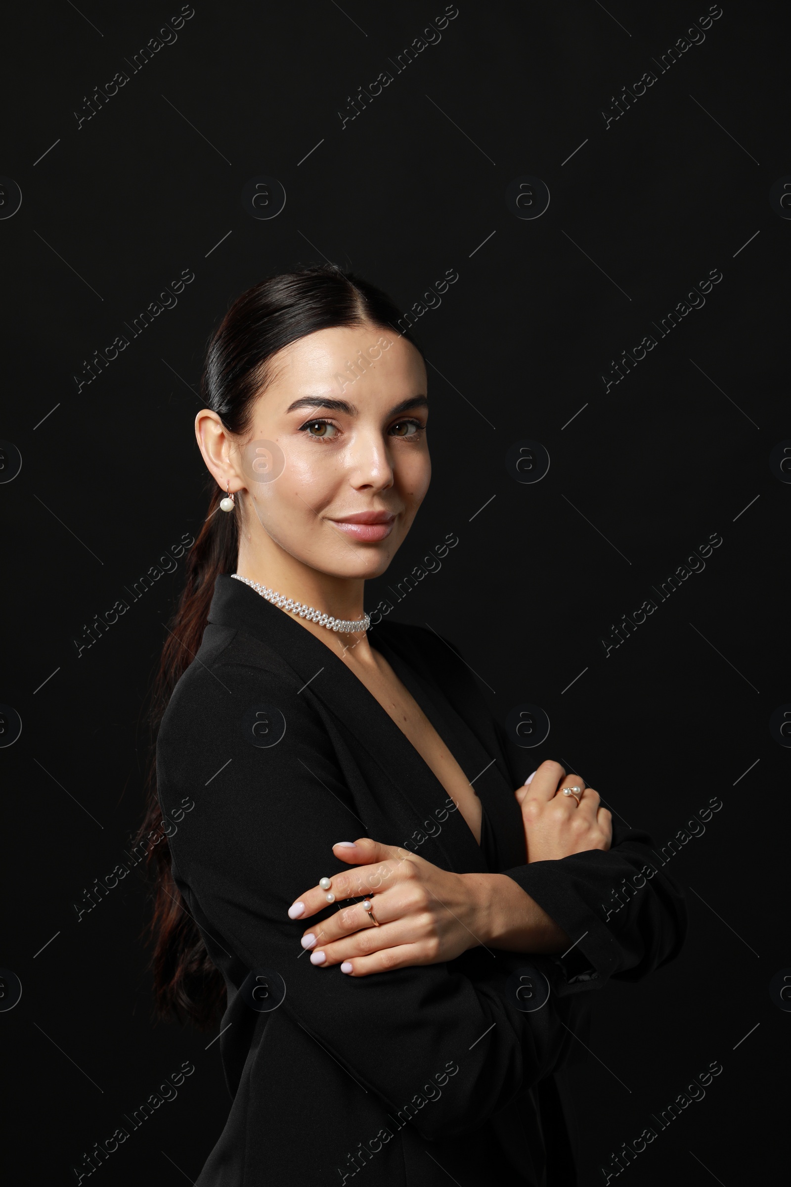 Photo of Young woman with elegant pearl jewelry on black background