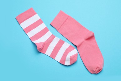 Photo of Different pink socks on light blue background, flat lay