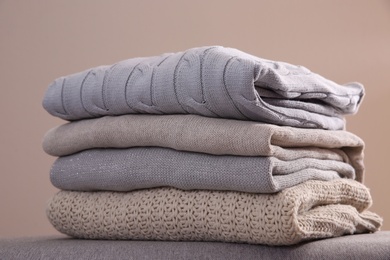 Stack of folded warm sweaters against grey background, closeup