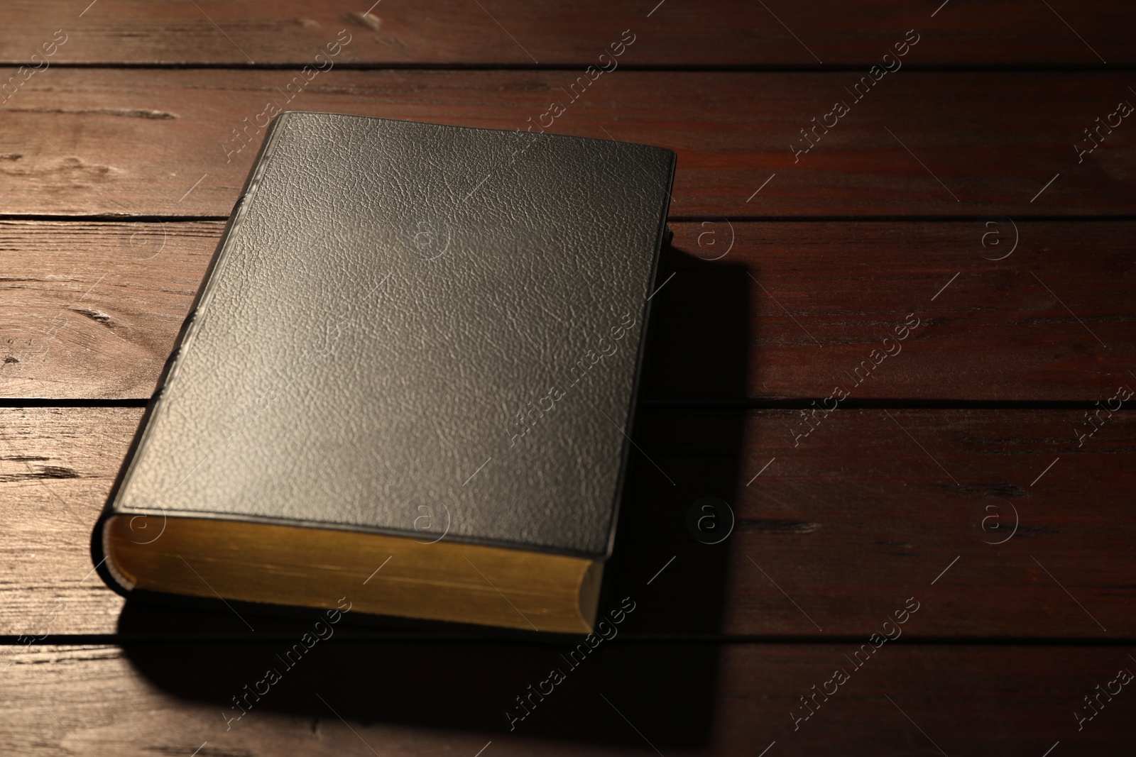Photo of Old hardcover Bible on wooden table, space for text. Religious book