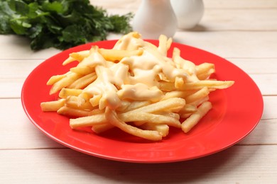 Delicious french fries with cheese sauce on wooden table, closeup