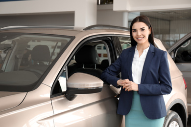 Photo of Young saleswoman near new car in dealership