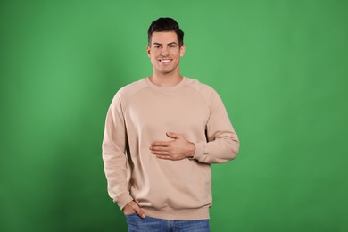 Photo of Happy healthy man touching his belly on green background
