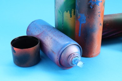 Photo of Spray paint cans and caps on light blue background