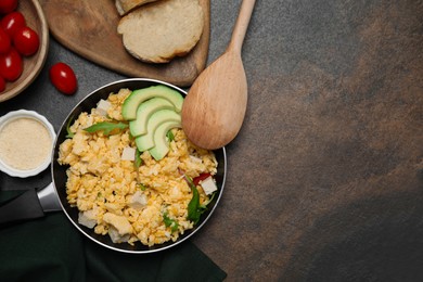 Frying pan with delicious scrambled eggs, tofu and avocado on textured table, flat lay. Space for text