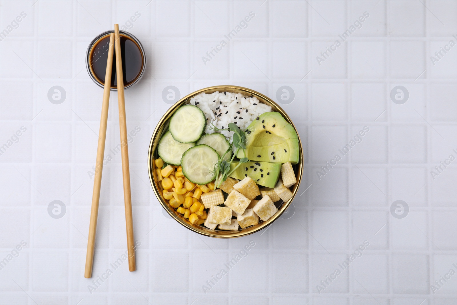 Photo of Delicious poke bowl with vegetables, tofu, avocado and microgreens served on white tiled table, flat lay