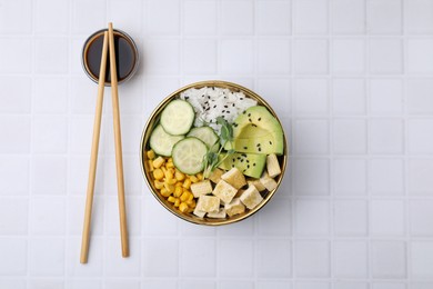 Delicious poke bowl with vegetables, tofu, avocado and microgreens served on white tiled table, flat lay