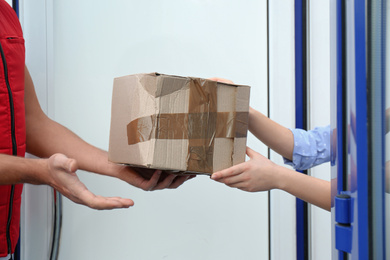 Photo of Courier giving damaged cardboard box to client, closeup. Poor quality delivery service