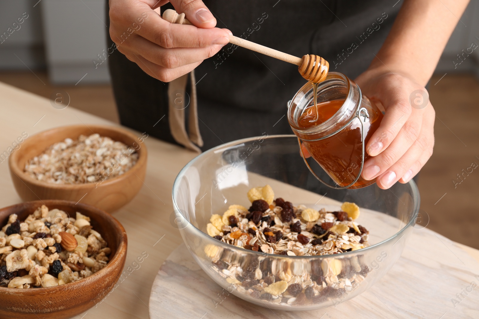 Photo of Woman preparing healthy granola bar at wooden table in kitchen