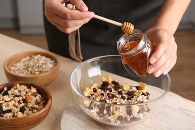 Woman preparing healthy granola bar at wooden table in kitchen