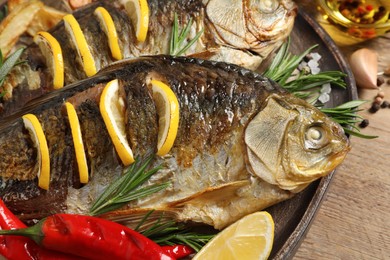 Photo of Tasty homemade roasted crucian carps served on wooden table, closeup. River fish