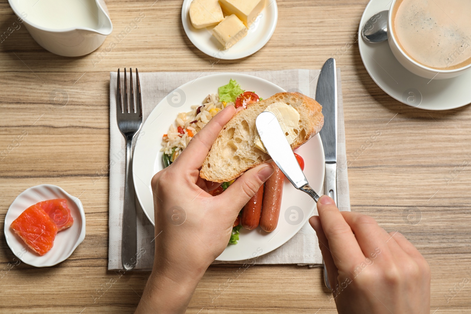 Photo of Woman spreading butter on toast at table, top view. Buffet service