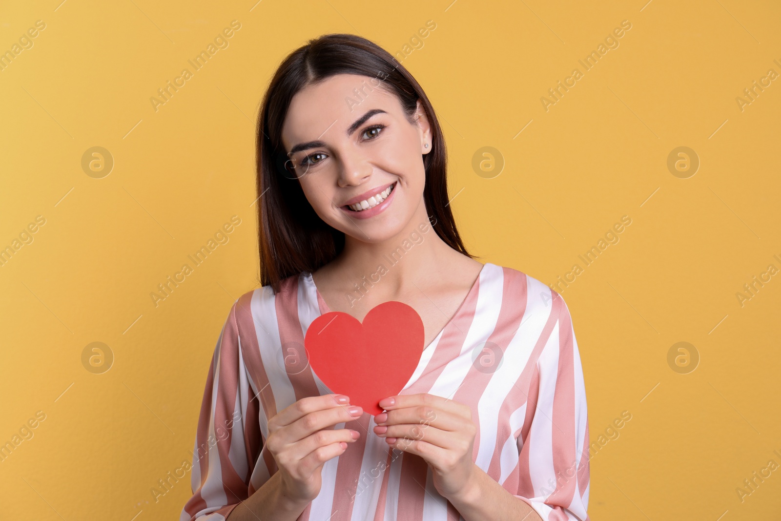 Photo of Portrait of young woman with paper heart on color background