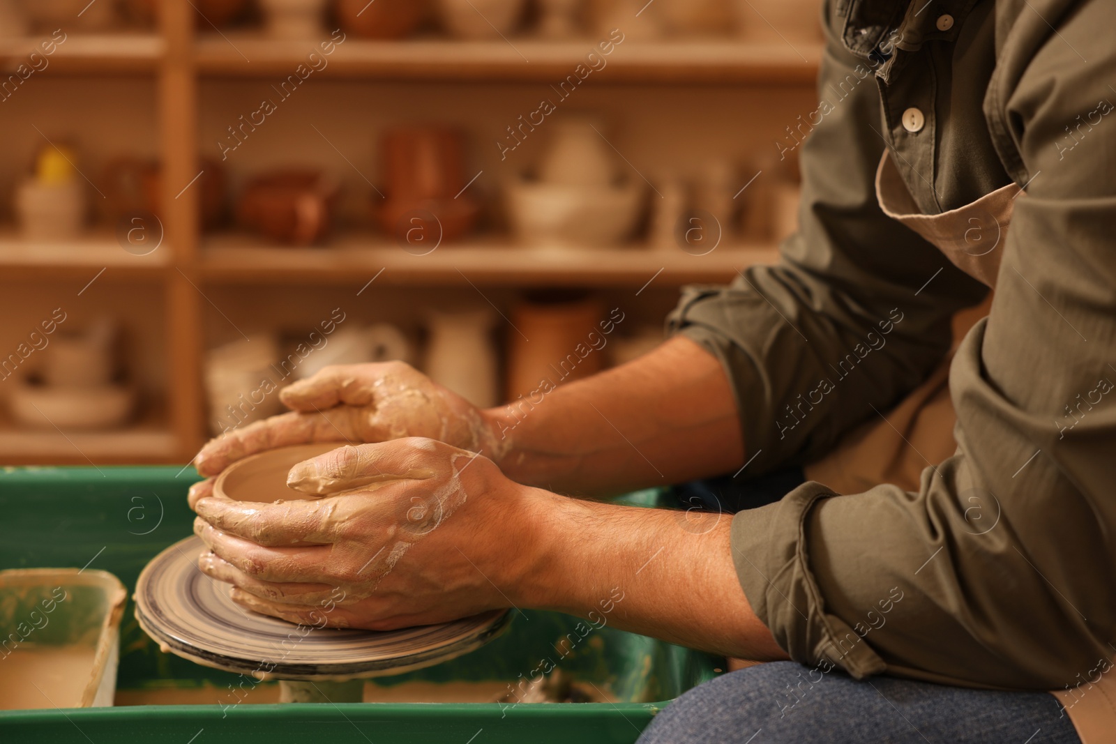 Photo of Clay crafting. Man making bowl on potter's wheel indoors, closeup