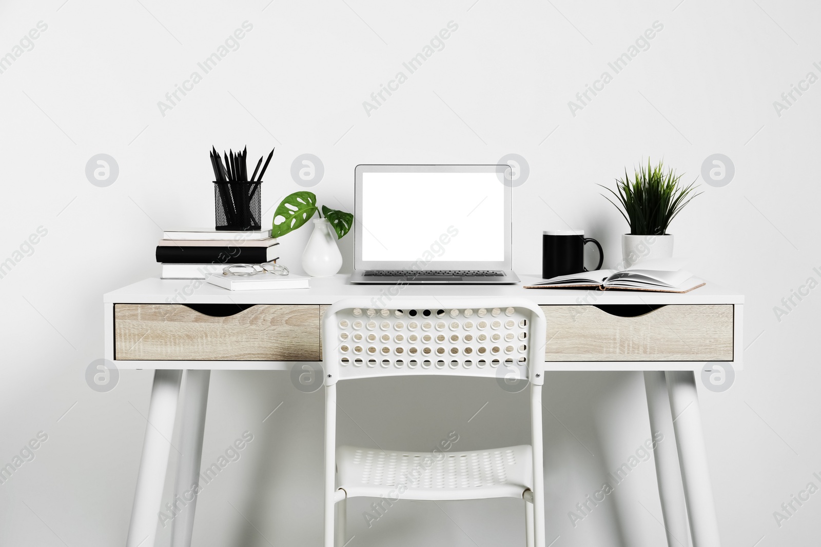 Photo of Cozy workspace with laptop, houseplants and stationery on wooden desk at home