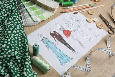 Photo of Sketch of fashion clothes and thread supplies at designer's workplace