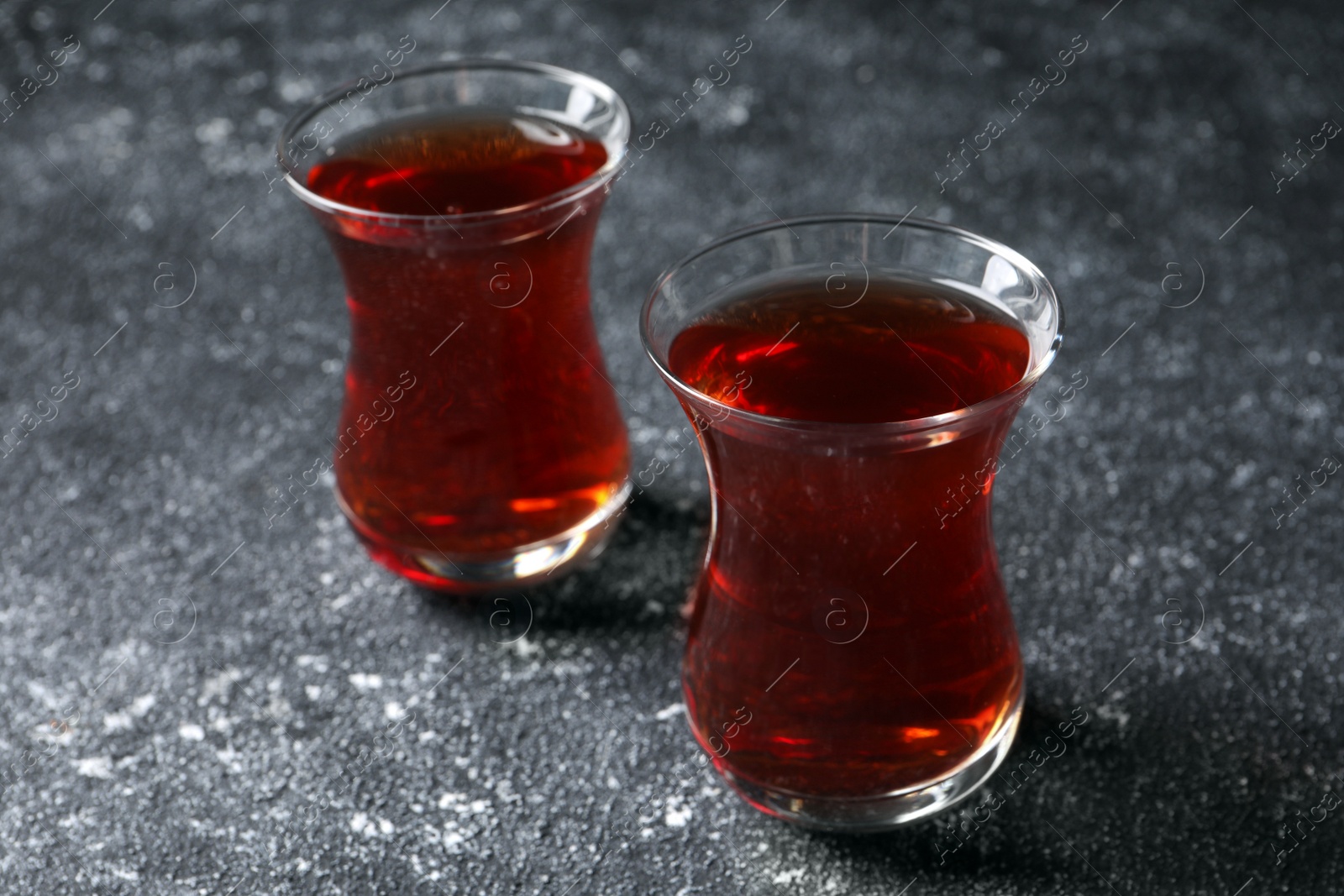 Photo of Glasses of traditional Turkish tea on grey textured table, closeup