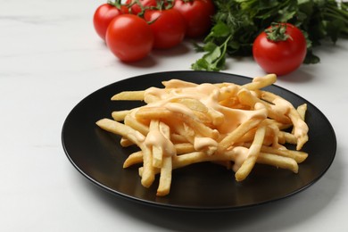 Photo of Delicious French fries with cheese sauce, tomatoes and parsley on white table, closeup