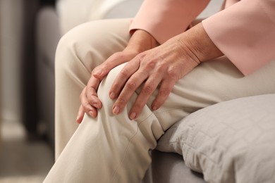 Mature woman suffering from knee pain indoors, closeup. Rheumatism symptom
