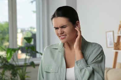 Photo of Young woman suffering from ear pain at home