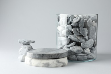 Photo of Presentation for product. Podium and glass container with stones on light grey background. Space for text