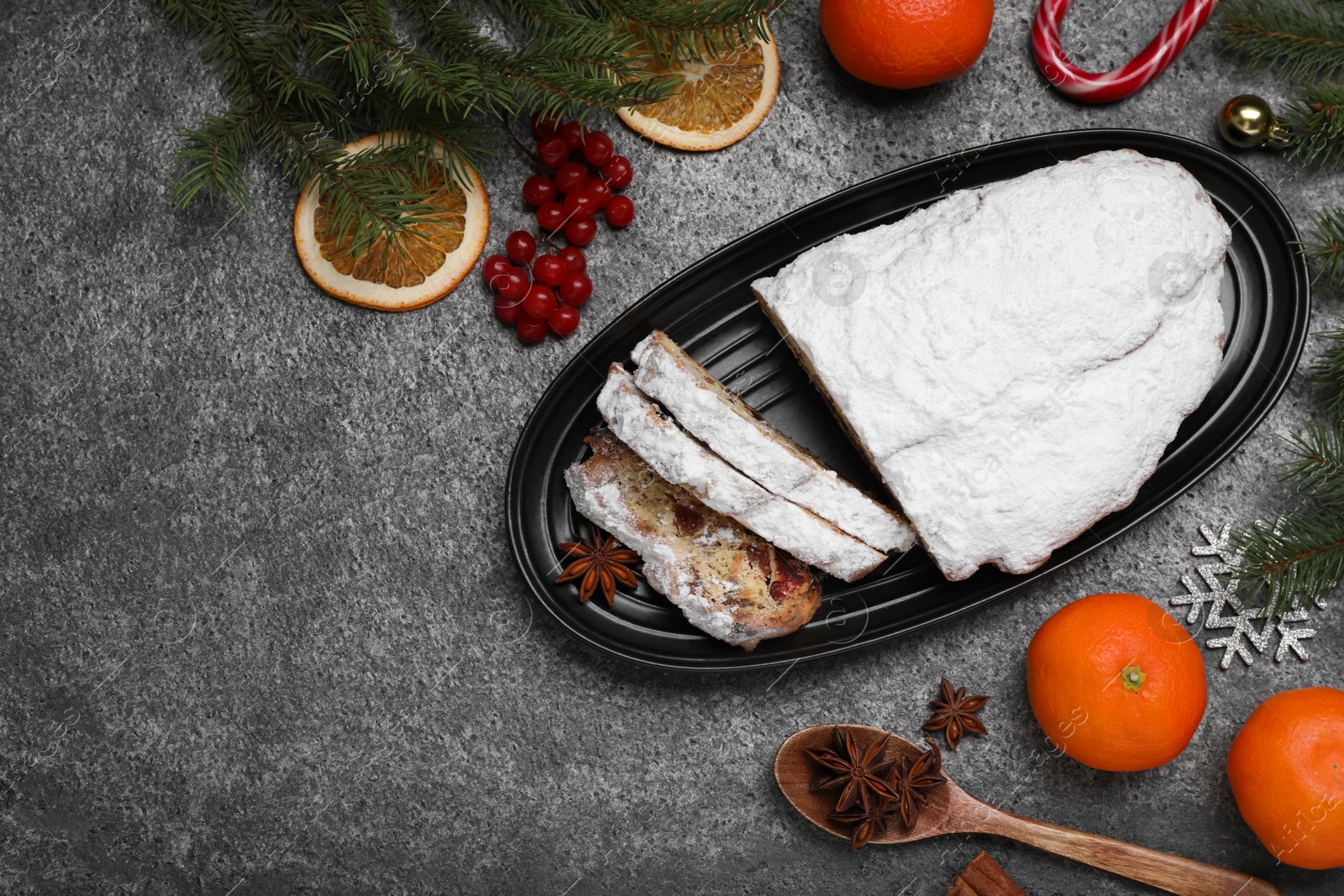 Photo of Traditional Christmas Stollen with icing sugar on grey table, flat lay. Space for text