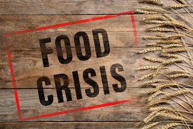 Image of Global food crisis concept. Wheat spikes on wooden background, flat lay