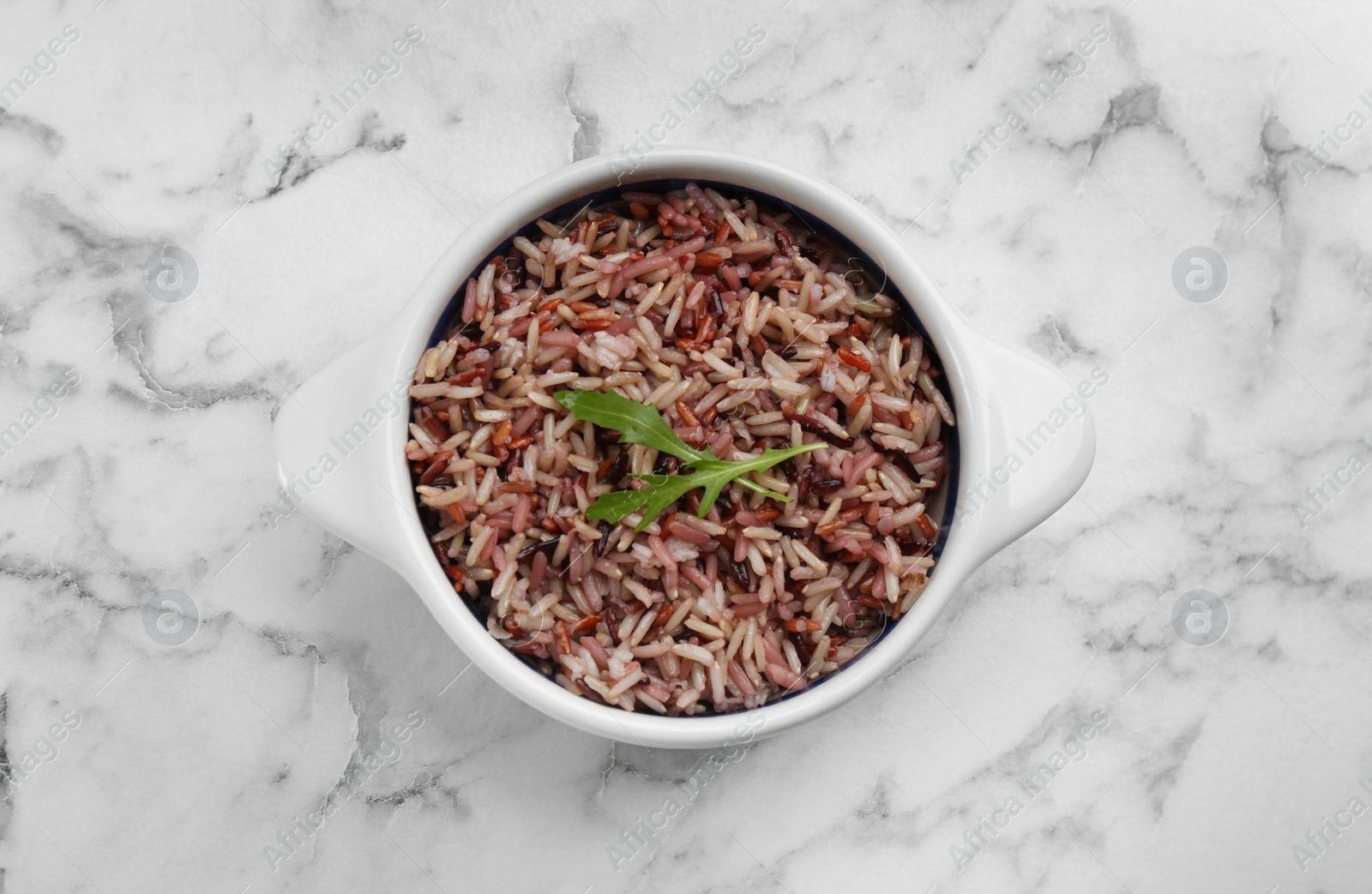 Photo of Tasty brown rice on marble table, top view