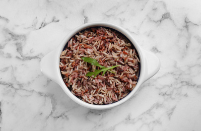 Tasty brown rice on marble table, top view