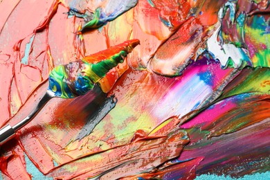 Photo of Mixed colorful acrylics and painting knife on canvas, closeup view