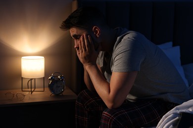 Frustrated man suffering from insomnia on bed