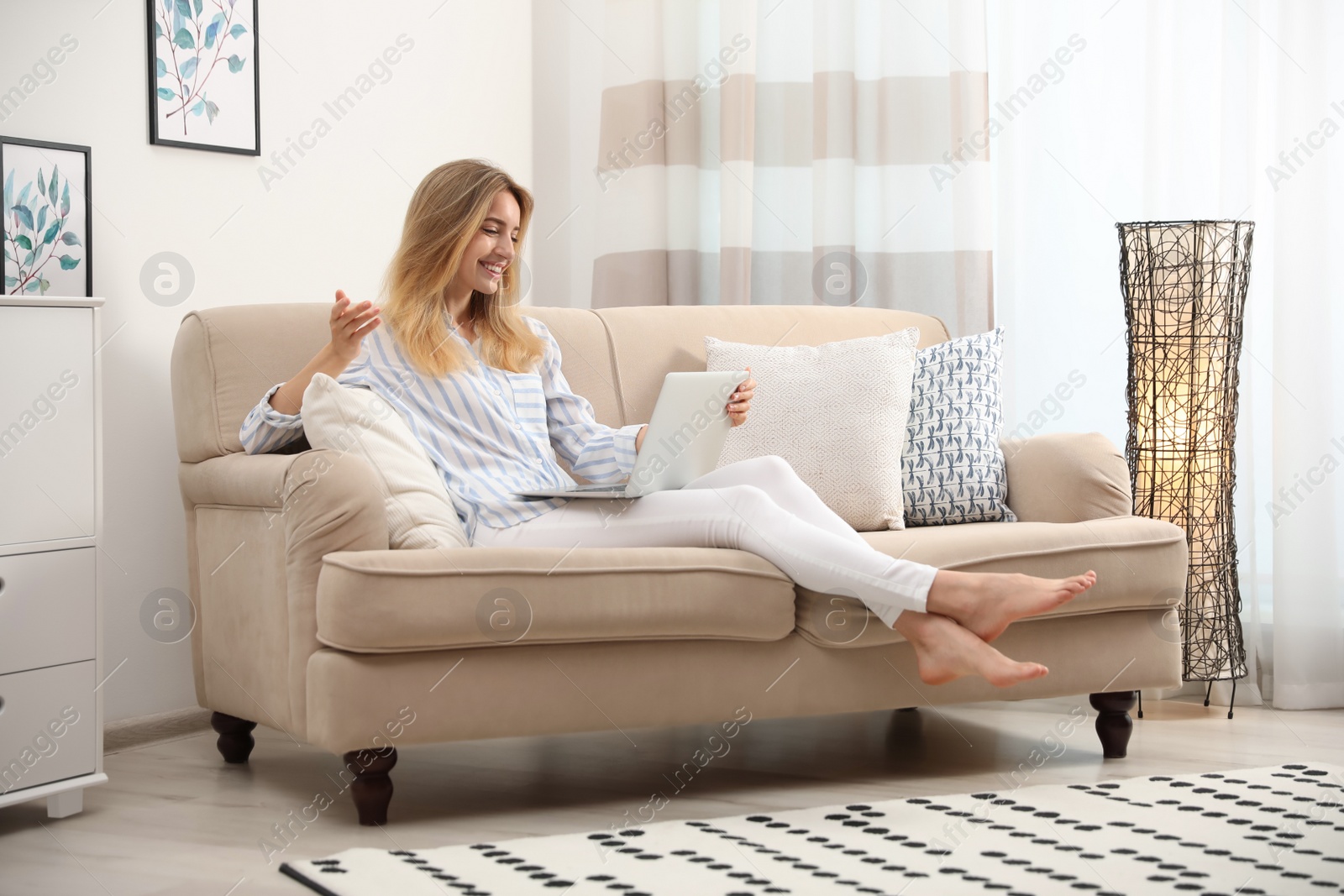 Photo of Pretty young woman with laptop sitting on sofa at home