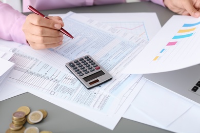 Photo of Young female calculating taxes at table, closeup