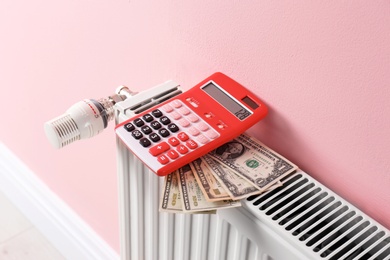 Heating radiator with calculator and money on color wall