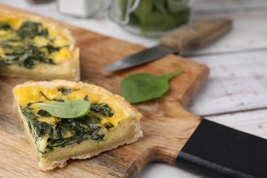 Photo of Piece of delicious pie with spinach on white wooden table, closeup. Space for text