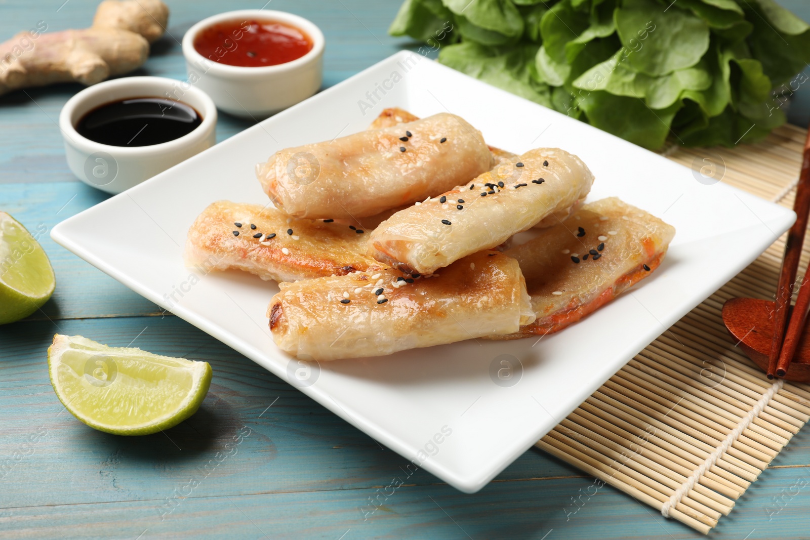 Photo of Tasty fried spring rolls served on light blue wooden table, closeup