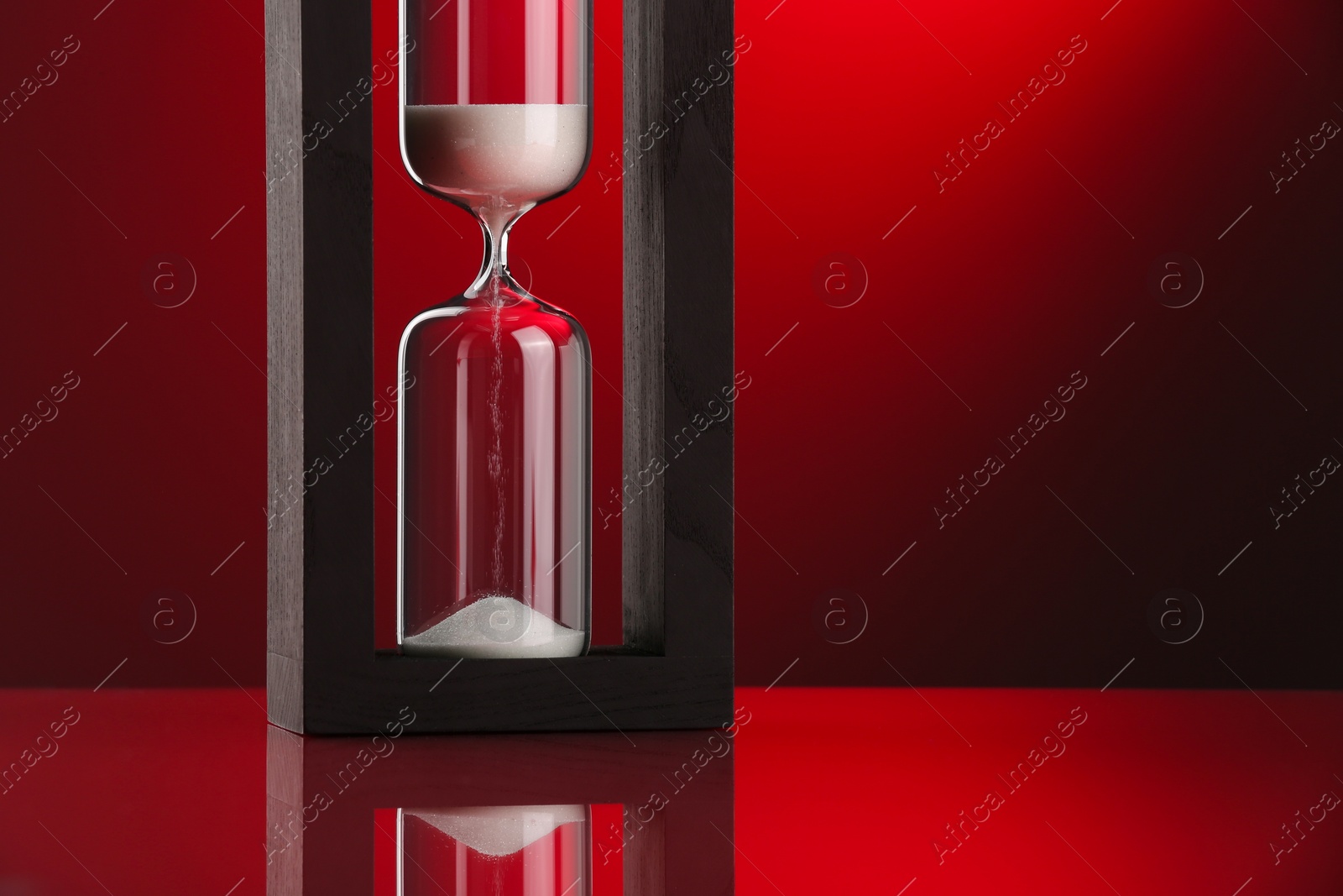 Photo of Hourglass with flowing sand against color background. Space for text