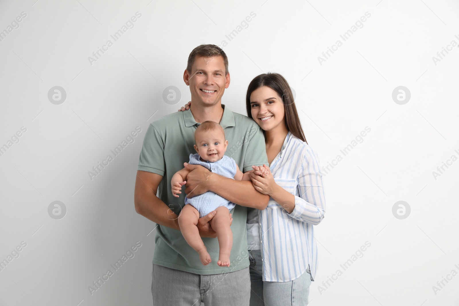 Photo of Portrait of happy family with their cute baby on white background