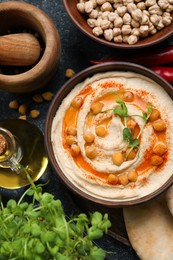 Photo of Delicious hummus with chickpeas and different ingredients on grey table, flat lay