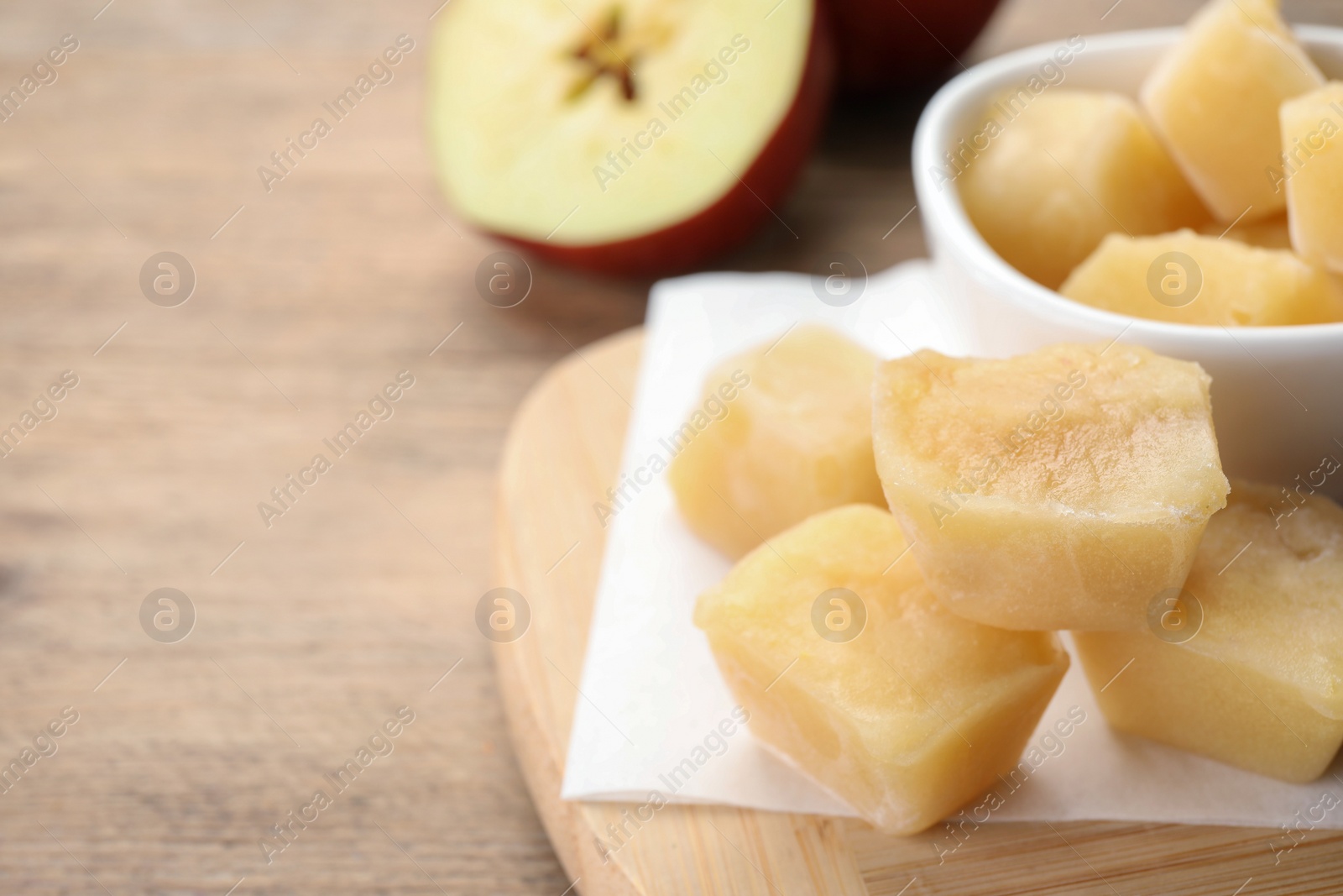 Photo of Frozen apple puree cubes and ingredient on wooden table, closeup. Space for text