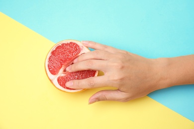 Young woman touching half of grapefruit on color background, closeup. Sex concept