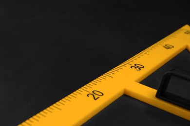 Photo of Yellow school triangle on blackboard, closeup. Space for text