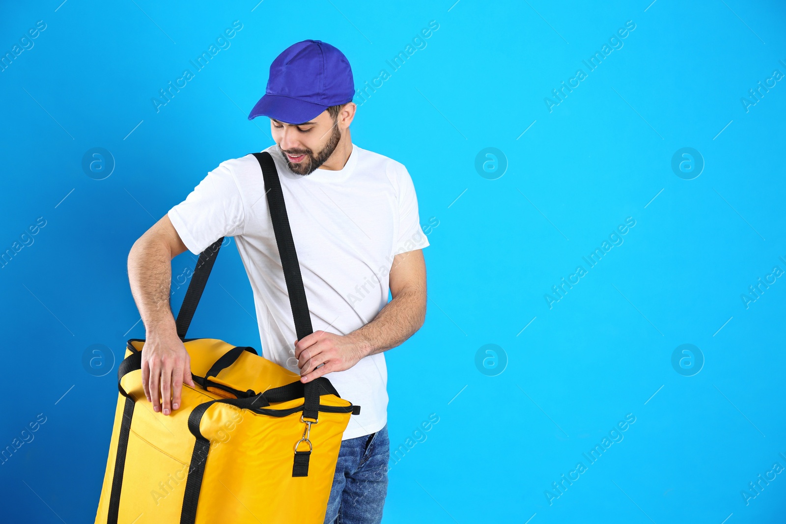 Photo of Courier with thermo bag on light blue background, space for text. Food delivery service