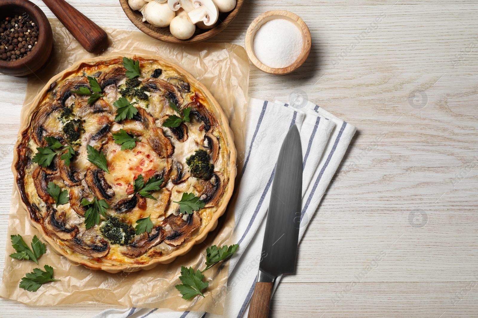 Photo of Delicious quiche with mushrooms and ingredients on white wooden table, flat lay. Space for text