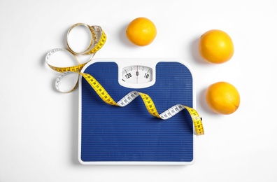 Photo of Composition with scales, oranges and tape measure on white background, top view