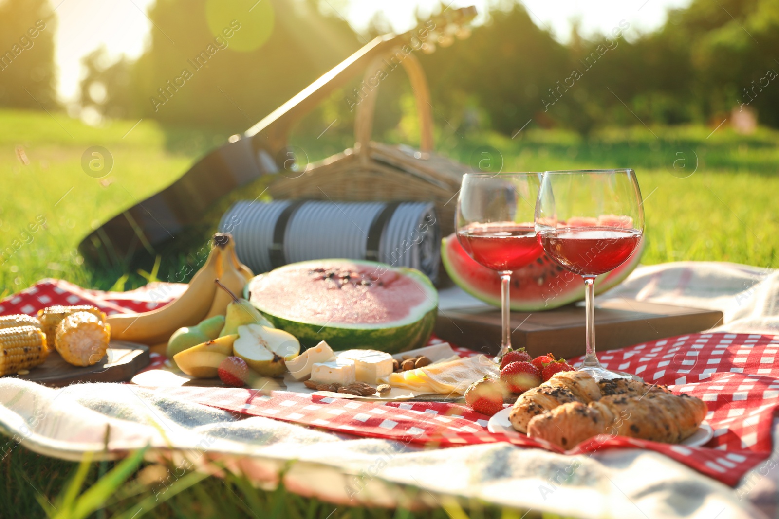 Photo of Picnic blanket with delicious food and drinks outdoors on sunny day