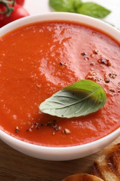 Photo of Delicious tomato soup with basil and spices on table, closeup